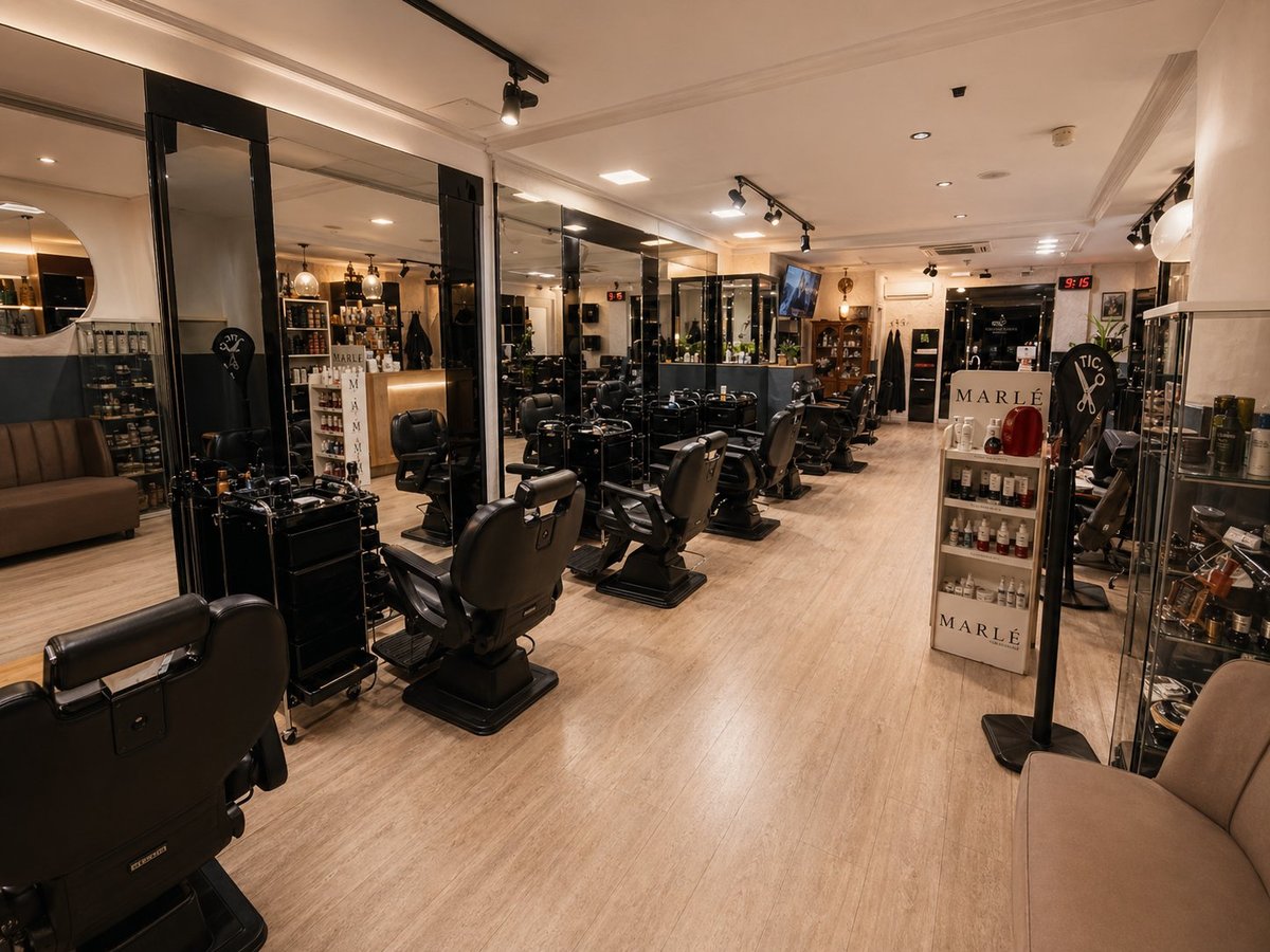 Modern hair salon interior with multiple styling stations, mirrors, and black chairs along wooden flooring under warm lighting